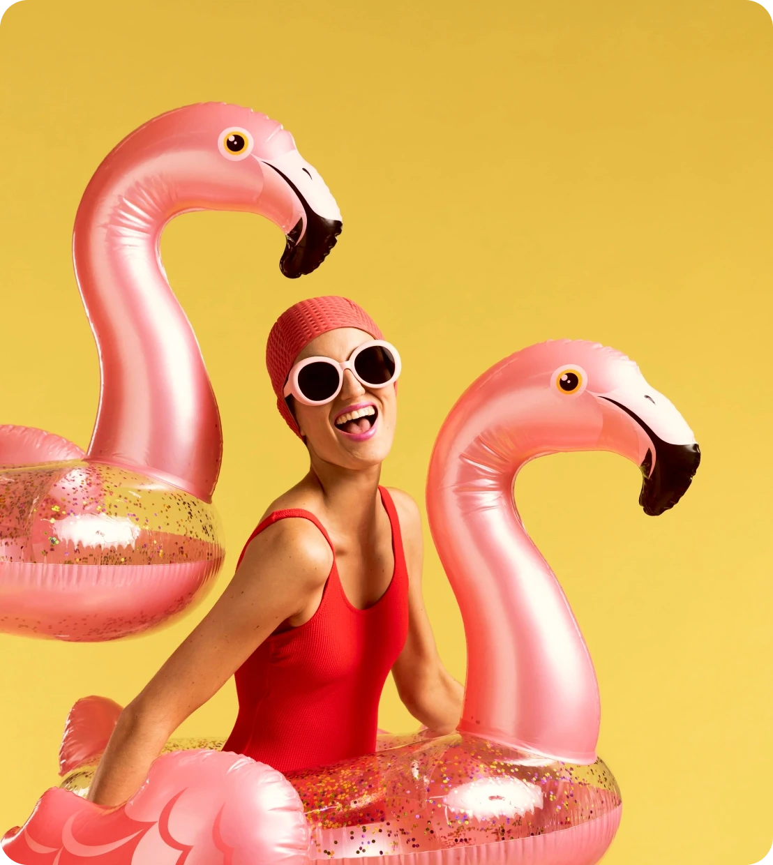 Woman between flamingo pool floats on a yellow background