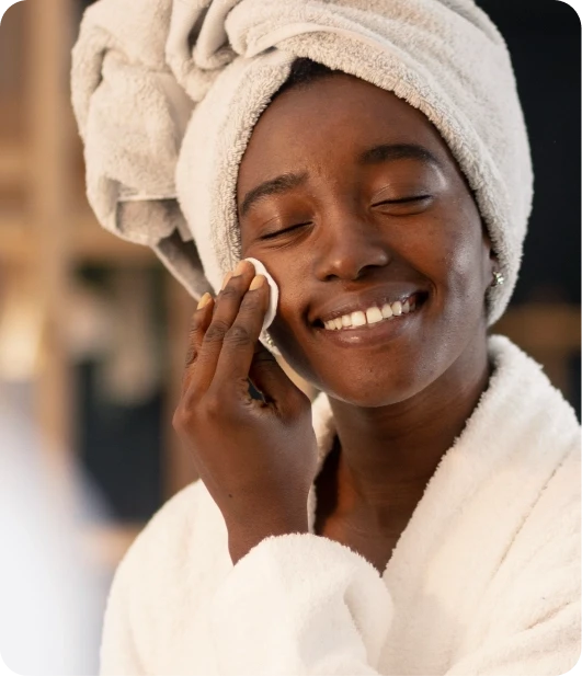 Woman in a towel using a Refreshify wipe on her face